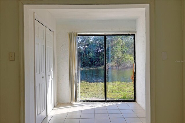 doorway to outside with light tile patterned floors and a textured wall