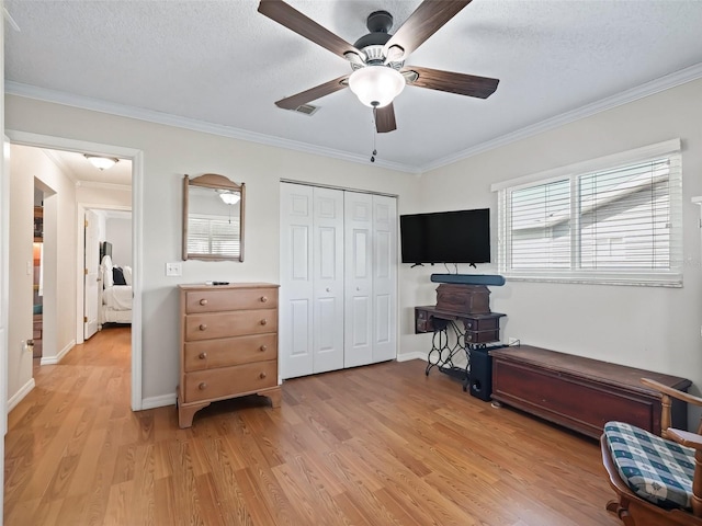 interior space featuring crown molding, ceiling fan, a textured ceiling, and light wood-type flooring