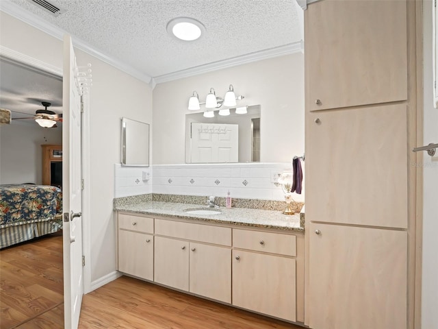 bathroom featuring tasteful backsplash, wood-type flooring, ornamental molding, vanity, and a textured ceiling