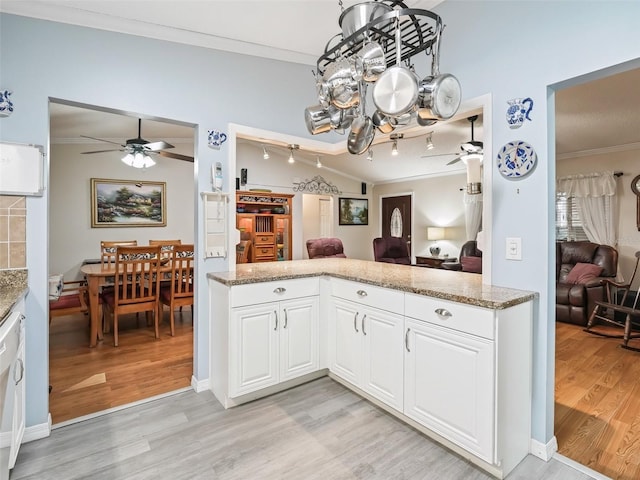 kitchen with ceiling fan with notable chandelier, ornamental molding, light hardwood / wood-style floors, and white cabinets