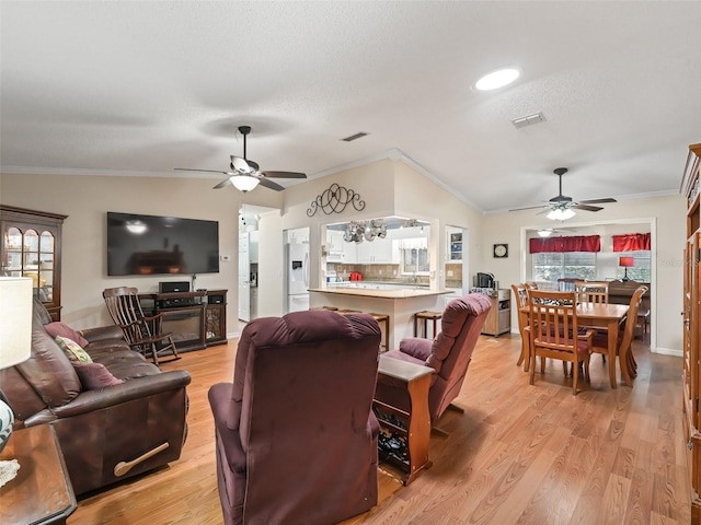 living room featuring ornamental molding, vaulted ceiling, and light wood-type flooring