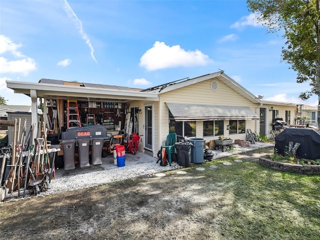 rear view of house featuring a lawn and solar panels