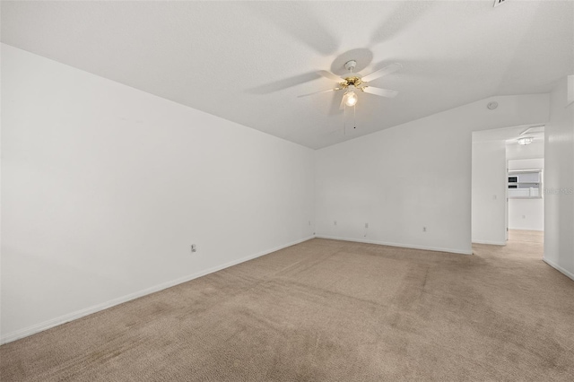 carpeted spare room featuring vaulted ceiling, a textured ceiling, and ceiling fan