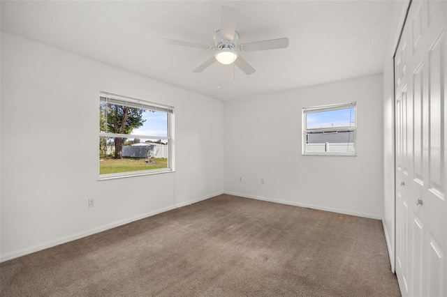 unfurnished room featuring ceiling fan and carpet