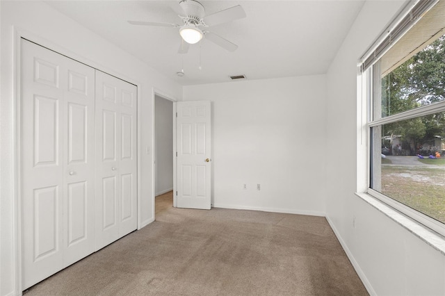 unfurnished bedroom with light carpet, a closet, and ceiling fan