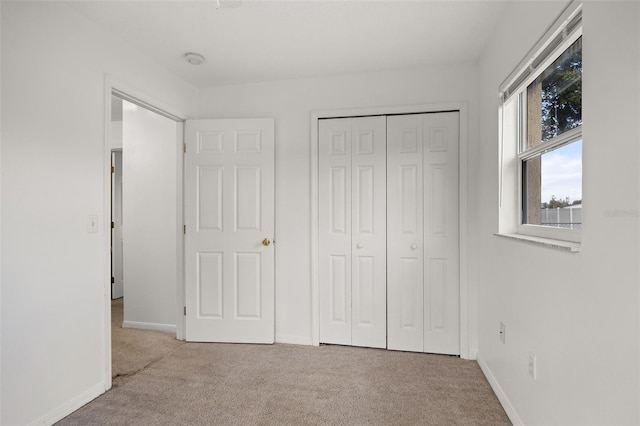 unfurnished bedroom featuring a closet and light carpet