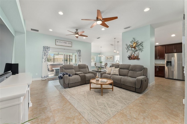 tiled living room with ceiling fan with notable chandelier