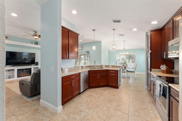 kitchen with pendant lighting, sink, appliances with stainless steel finishes, ceiling fan with notable chandelier, and kitchen peninsula