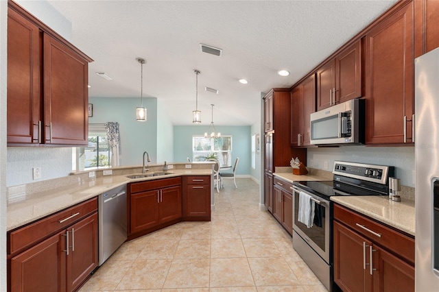 kitchen featuring sink, light stone counters, hanging light fixtures, appliances with stainless steel finishes, and a healthy amount of sunlight