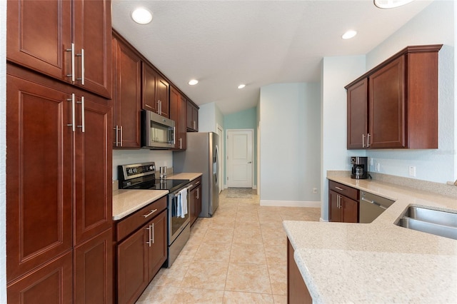 kitchen featuring sink, vaulted ceiling, light tile patterned floors, appliances with stainless steel finishes, and light stone countertops