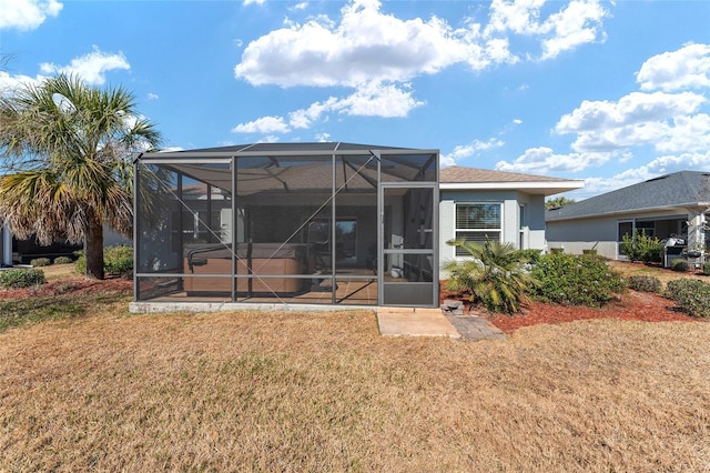 back of property featuring a lanai and a lawn