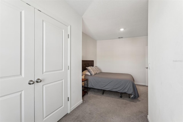 carpeted bedroom featuring a textured ceiling and a closet