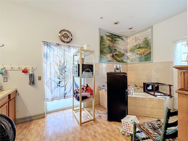 bathroom featuring tile patterned flooring, tiled tub, and vanity