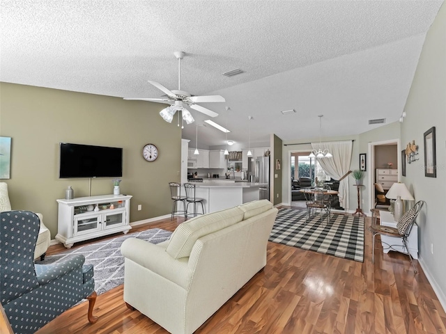 living room featuring lofted ceiling, ceiling fan with notable chandelier, a textured ceiling, and dark hardwood / wood-style flooring