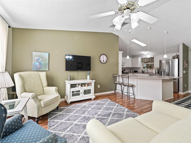 living room featuring ceiling fan, vaulted ceiling, hardwood / wood-style floors, and a textured ceiling