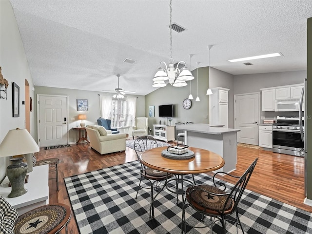 dining room with lofted ceiling, a textured ceiling, and light wood-type flooring