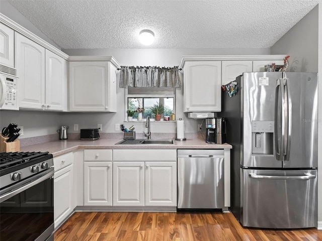 kitchen with stainless steel appliances, sink, and white cabinets