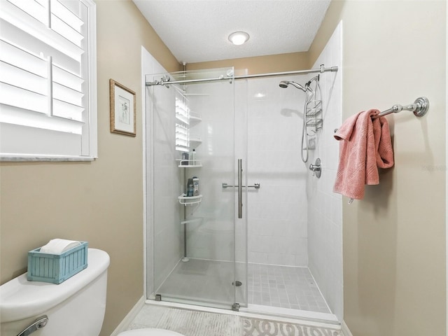 bathroom with toilet, an enclosed shower, and a textured ceiling