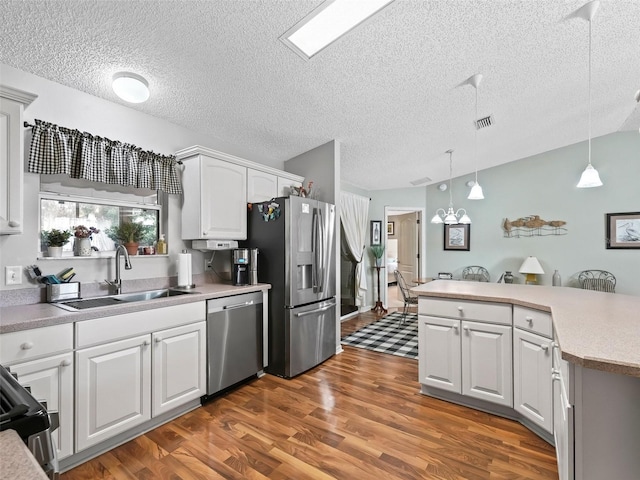 kitchen with pendant lighting, sink, stainless steel appliances, dark hardwood / wood-style floors, and white cabinets