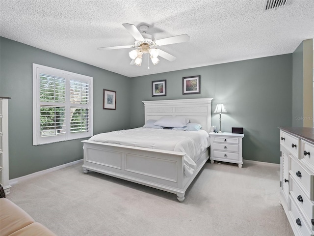 bedroom featuring light carpet, a textured ceiling, and ceiling fan