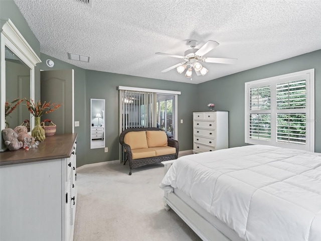 bedroom with ceiling fan, light colored carpet, and a textured ceiling