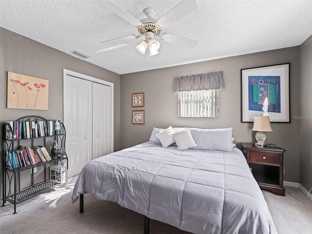 bedroom with light carpet, a textured ceiling, a closet, and ceiling fan