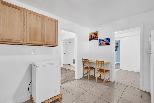 kitchen with light tile patterned flooring, fridge, and light brown cabinetry