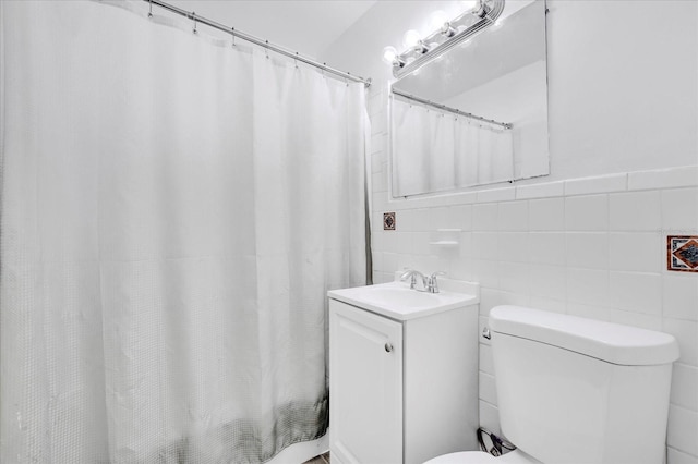 bathroom with walk in shower, vanity, toilet, and tile walls