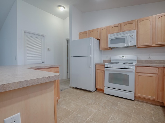 kitchen with white appliances, lofted ceiling, and light brown cabinets