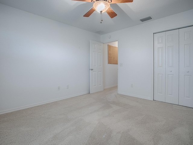 unfurnished bedroom featuring ceiling fan, light colored carpet, and a closet