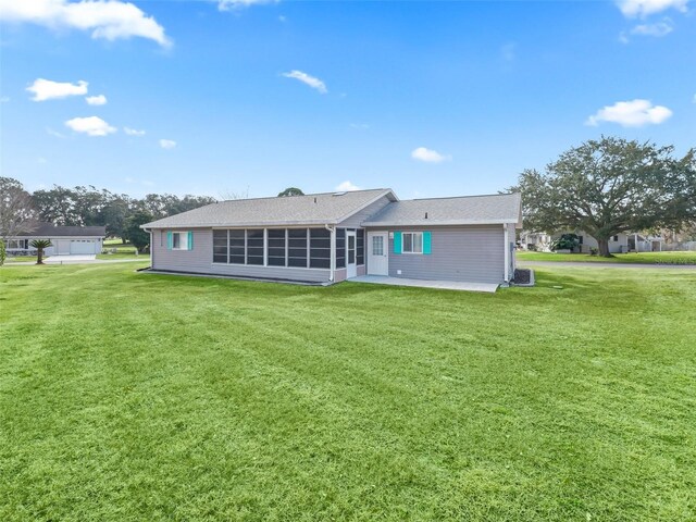 rear view of house with a sunroom, a patio, and a lawn