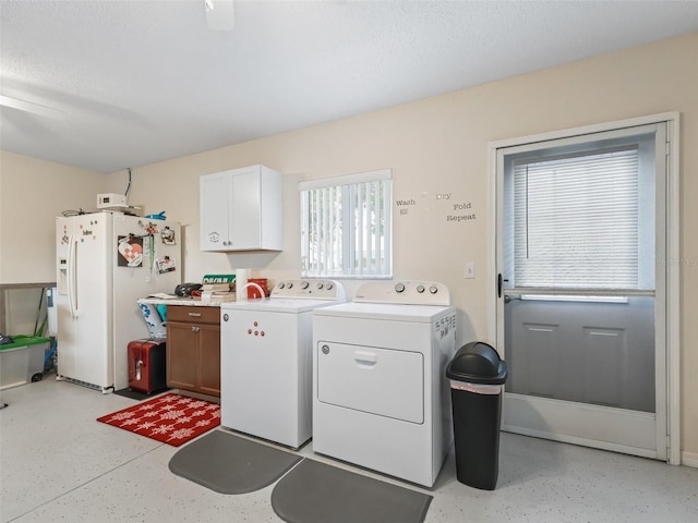 washroom featuring cabinets, washing machine and dryer, and a textured ceiling