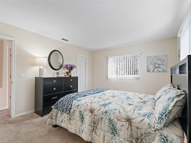 bedroom with light colored carpet and a textured ceiling