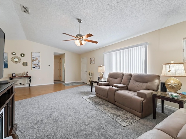 living room with wood-type flooring, a textured ceiling, vaulted ceiling, and ceiling fan