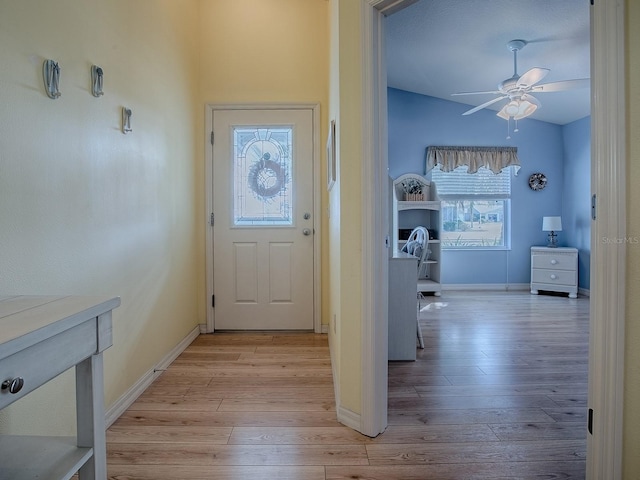 doorway featuring ceiling fan, vaulted ceiling, and light wood-type flooring