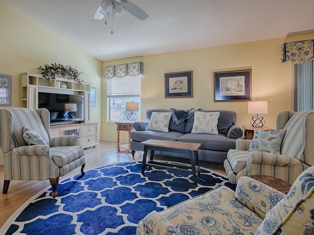 living room with ceiling fan, lofted ceiling, light hardwood / wood-style floors, and a textured ceiling