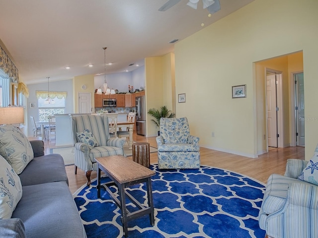 living room with ceiling fan, high vaulted ceiling, and light hardwood / wood-style floors