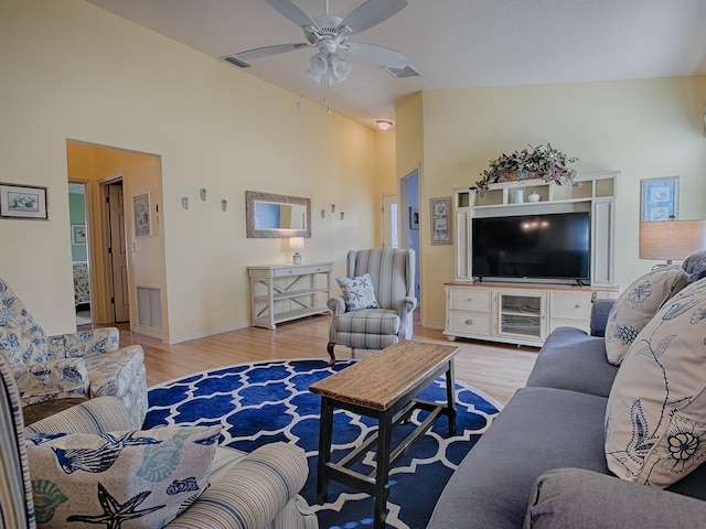 living room with ceiling fan, high vaulted ceiling, and light hardwood / wood-style flooring