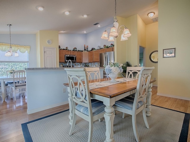 dining room featuring a notable chandelier, a high ceiling, and light wood-type flooring