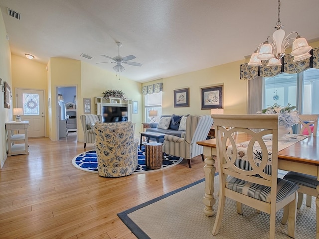 dining room featuring lofted ceiling, ceiling fan with notable chandelier, and light hardwood / wood-style flooring