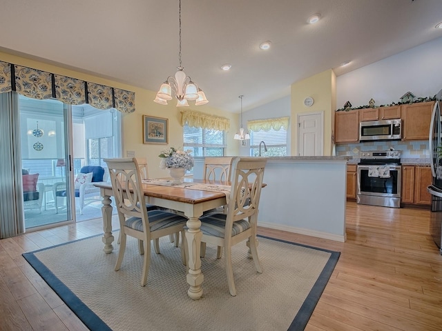 dining room featuring vaulted ceiling, a chandelier, and light wood-type flooring