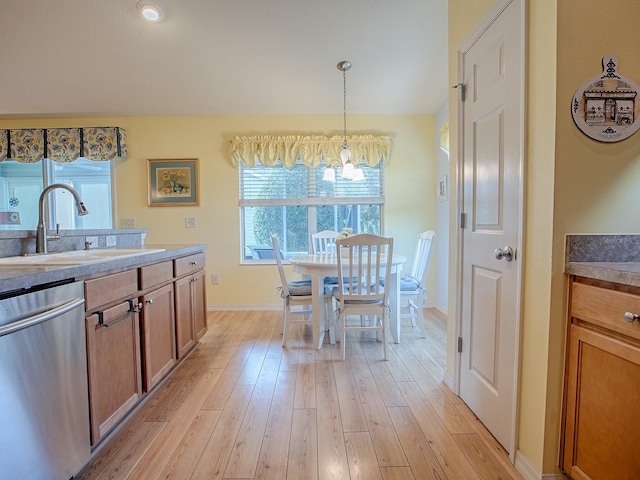 kitchen featuring pendant lighting, sink, a wealth of natural light, stainless steel dishwasher, and light wood-type flooring