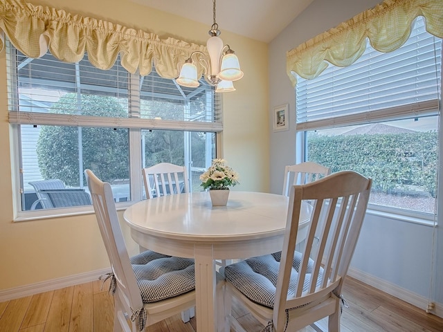 dining area with lofted ceiling, wood-type flooring, and a chandelier