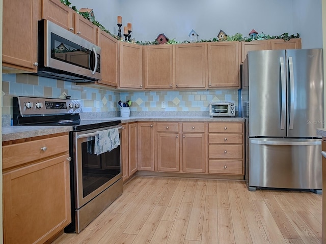 kitchen featuring appliances with stainless steel finishes, light hardwood / wood-style floors, and backsplash