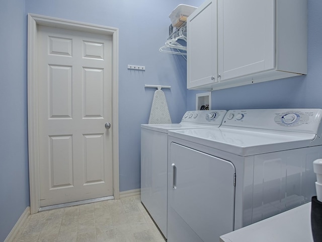 clothes washing area featuring cabinets and washer and dryer