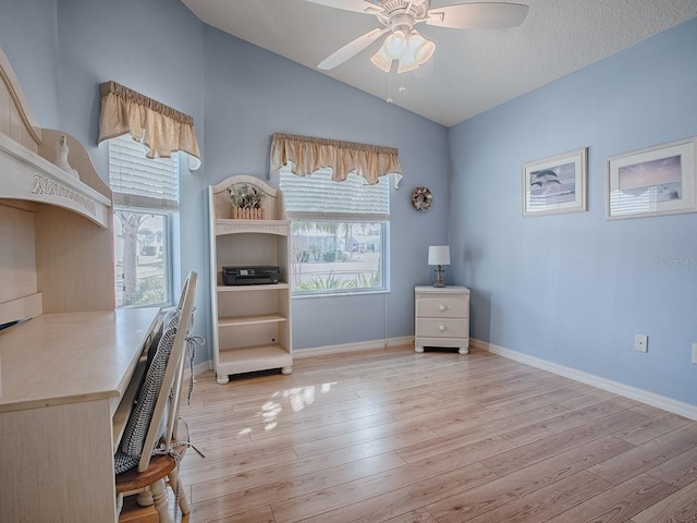 home office with lofted ceiling, a healthy amount of sunlight, ceiling fan, and light hardwood / wood-style flooring