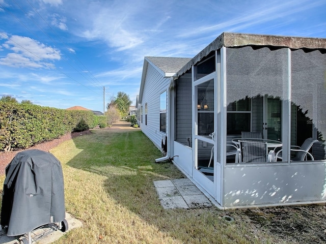 view of side of home featuring a sunroom and a yard