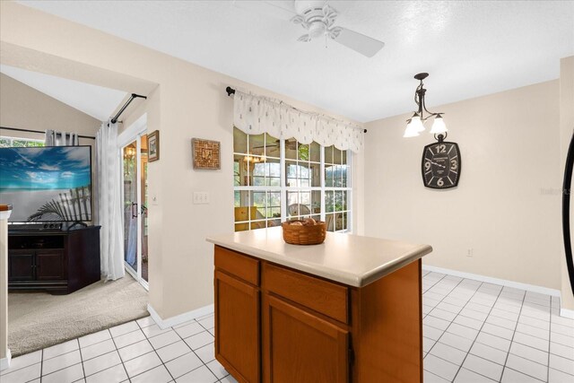 kitchen with lofted ceiling, light tile patterned floors, a kitchen island, pendant lighting, and ceiling fan