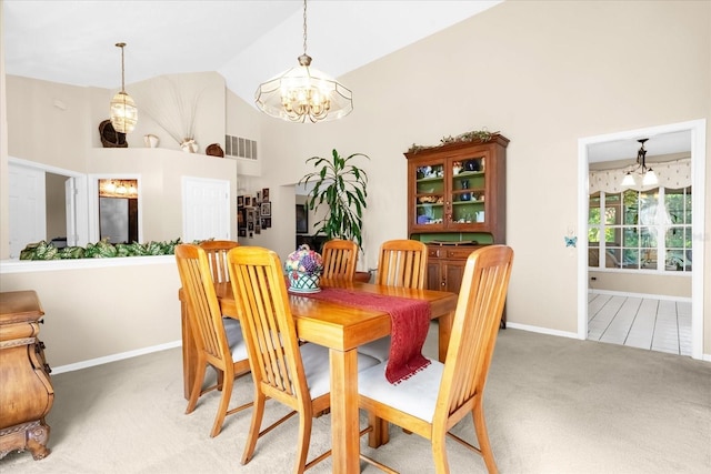 dining room with carpet, a notable chandelier, and high vaulted ceiling