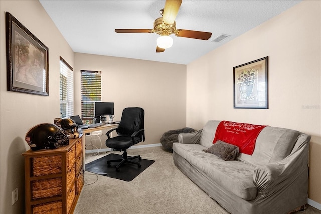 carpeted home office with a textured ceiling and ceiling fan